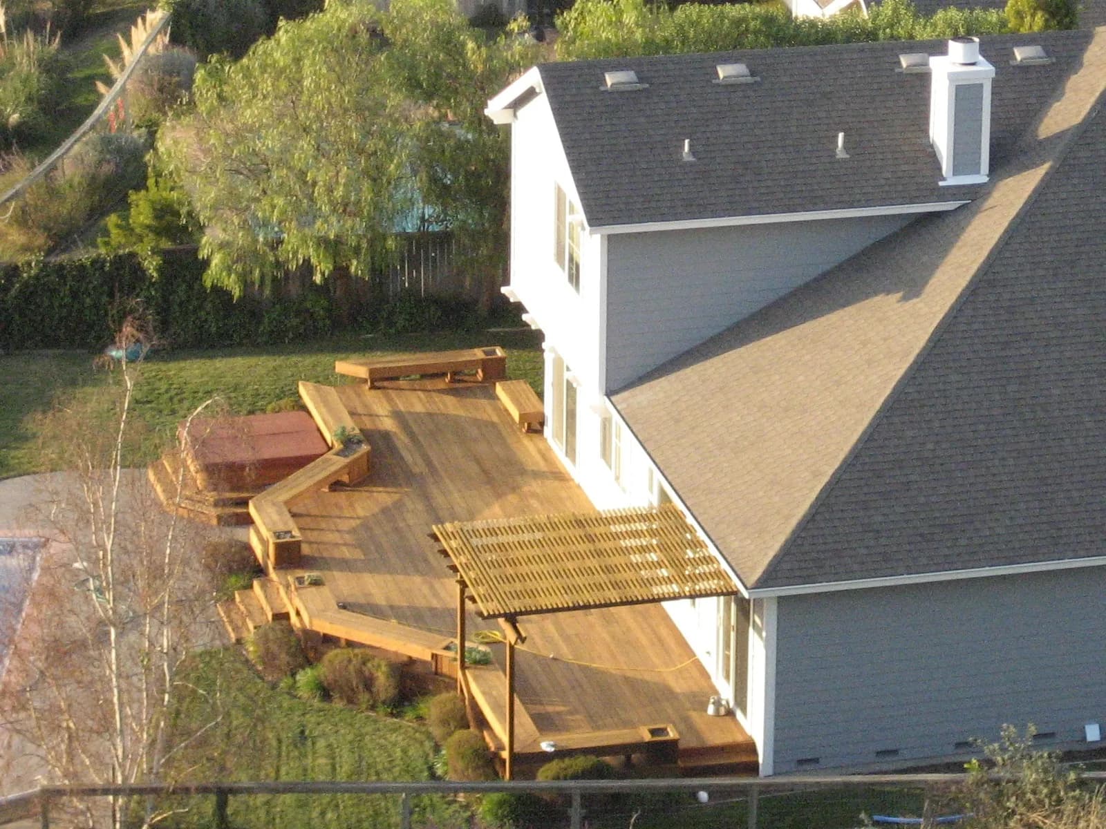 Aerial view of a new multi-level wood deck with a pergola and hot tub surround